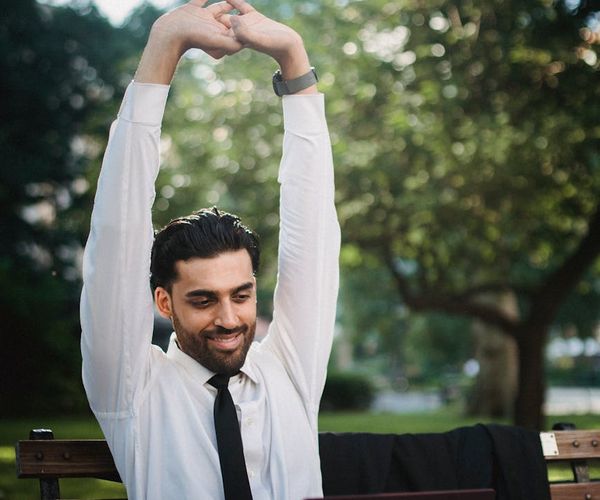 Person smiling and stretching outdoors in a natural park setting.